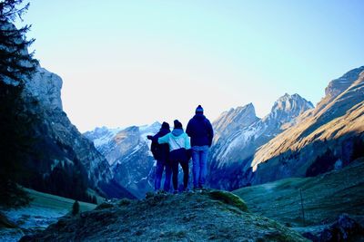 Rear view of people on snowcapped mountain against clear sky