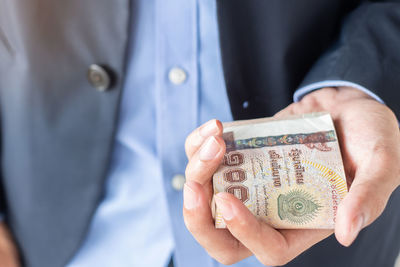 Midsection of businessman holding paper currencies