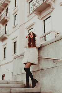 Full length portrait of young woman standing outside building