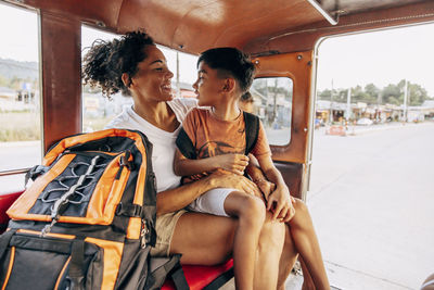 Son sitting on mother's lap while traveling in jinrikisha on vacation