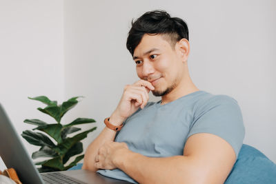 Portrait of young man using mobile phone while sitting on table