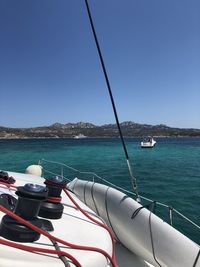 Sailboats moored on sea against clear blue sky