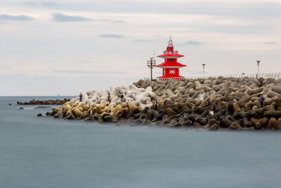 Lighthouse by sea against sky