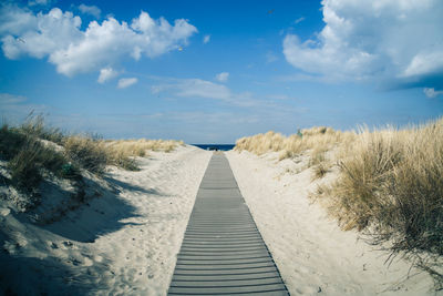 Boardwalk at beach against sky