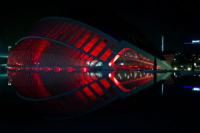 Illuminated bridge over river against sky in city at night