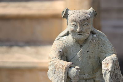 A smiling man stone ballast from china with blur background at wat bowonniwet vihara temple,bangkok