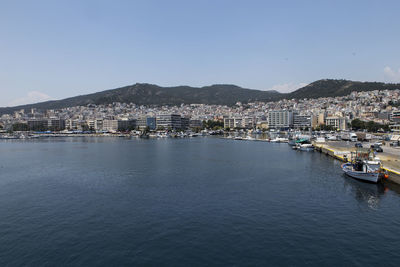 Sailboats in sea by city against clear sky