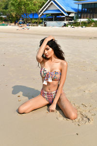 Portrait of sensuous young woman sitting on sand at beach