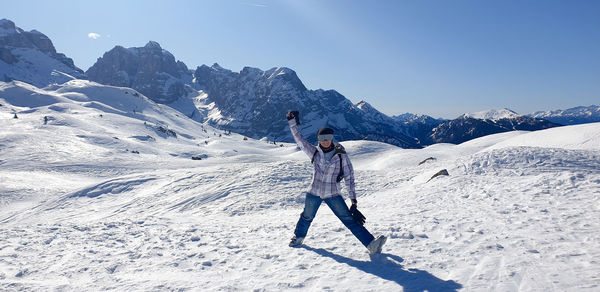 Woman standing on snowcapped mountain against sky