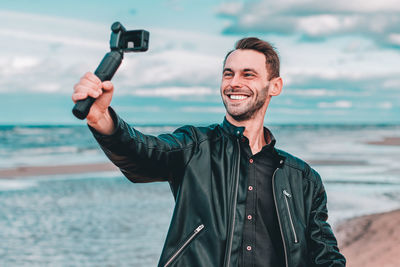 Man filming with video camera against sea