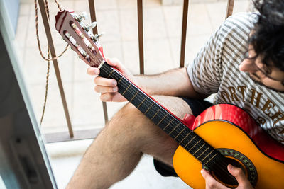 Midsection of man playing guitar