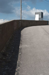 Empty footpath amidst buildings against sky