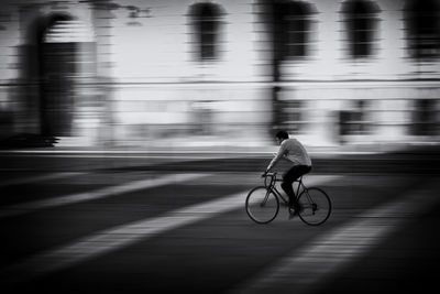 Blurred motion of man riding bicycle on street in city