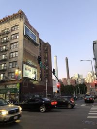 Traffic on road by buildings against clear sky