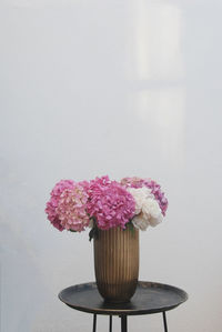 Close-up of pink flower vase on table against wall