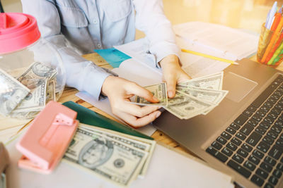 High angle view of businessman working with money and laptop on table