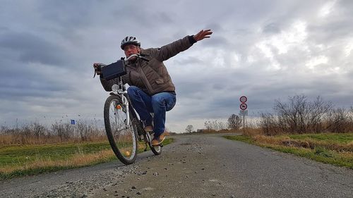 Man riding bicycle on road against sky