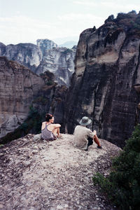 Rear view of men sitting on rock