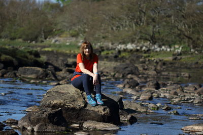 Woman sitting on rock at shore