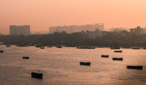 Scenic view of sea by buildings against sky during sunset