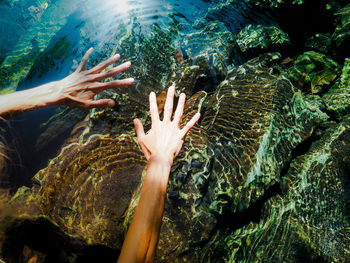 Cropped hands of woman gesturing over lake