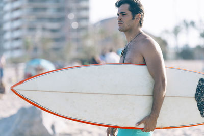 Side view of man holding surfboard at beach