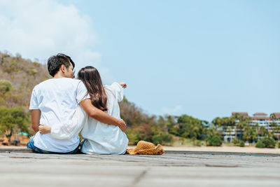 Rear view of couple sitting against sky