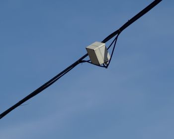 Low angle view of security camera against clear blue sky