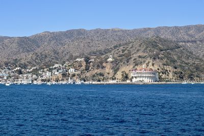 Scenic view of sea by buildings against clear blue sky