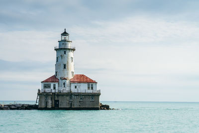 Lighthouse by sea against sky