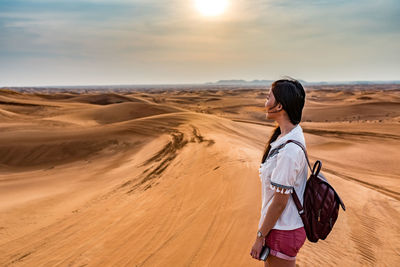 Woman standing in desert against sky