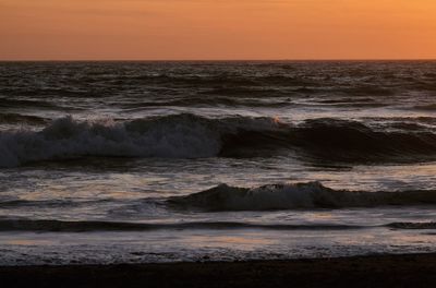 Scenic view of sea against dramatic sky during sunset