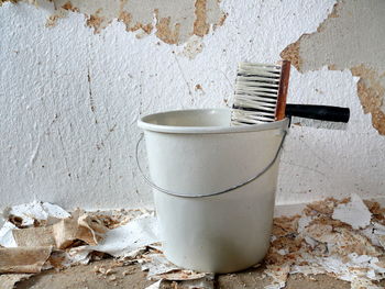 Brush and bucket against damaged wall