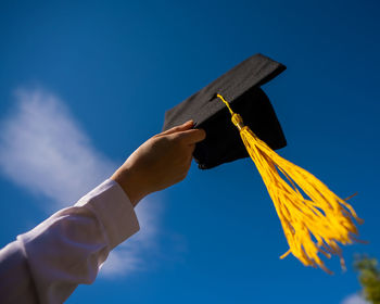 Low angle view of hand against blue sky