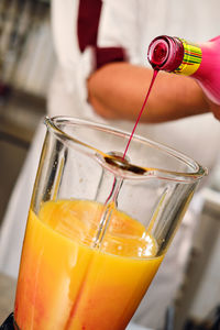 Close-up of hand pouring drink in glass