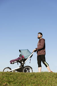 Low angle view of man walking with baby against sky