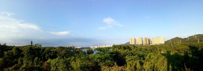 Panoramic view of trees and cityscape against sky