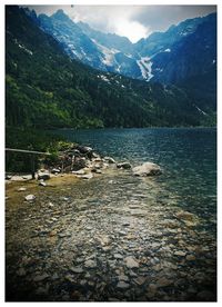 Scenic view of lake by mountains against sky