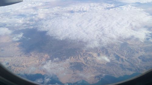 Aerial view of clouds over landscape seen from airplane window