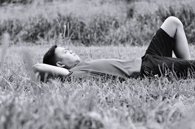 Portrait of young woman lying on grass in field