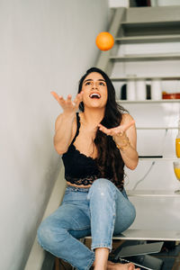 Young woman looking down while standing against wall