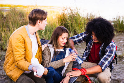 Side view of friends sitting on field