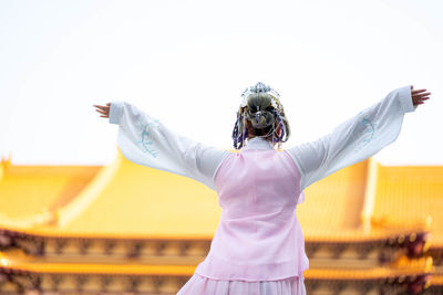 Rear view of woman photographing against sky