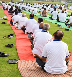 Group yoga exercise session for people of different age groups at cricket stadium in delhi