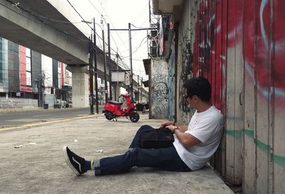Side view of man using mobile phone while sitting in building