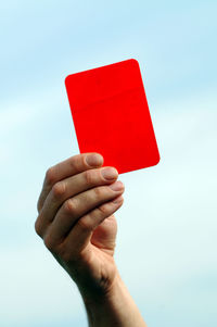Cropped hand of person holding box against blue background