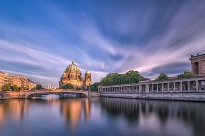 Bridge over river by cathedral against sky