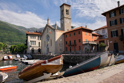 Boats moored in canal amidst buildings in city against sky