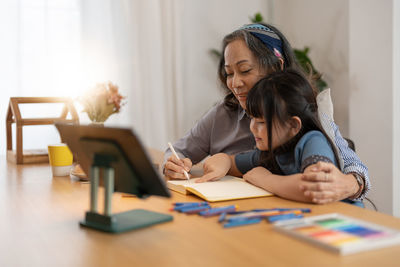 Grandmother teaching granddaughter at home