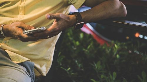 Midsection of man using mobile phone